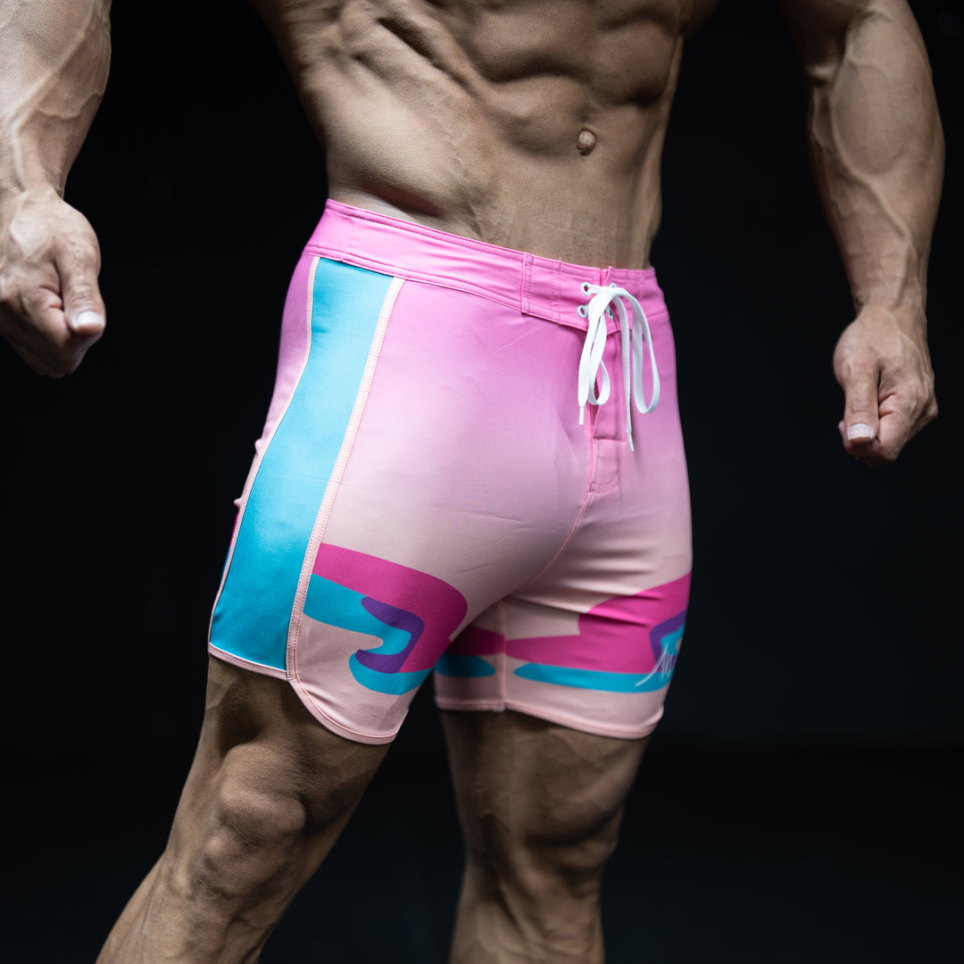 Muscular male athlete wearing Mirage pink, orange, and teal gradient Men&
